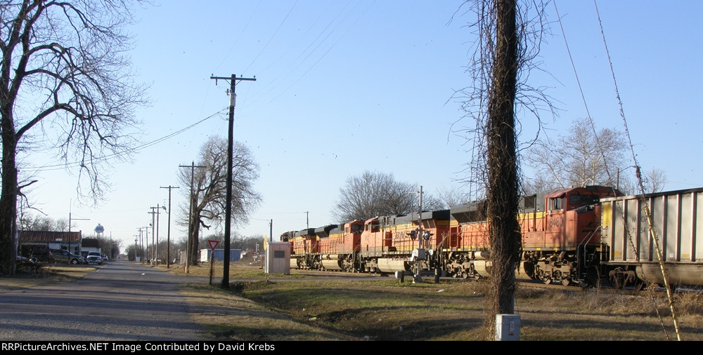 Four BNSF units pulling empty coal gons pass the second crossing.